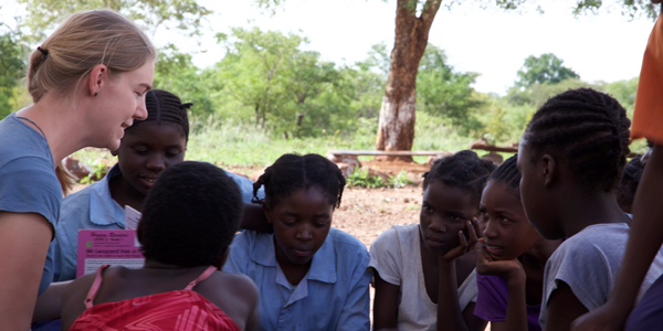 woman running an outdoor activity with a group of children