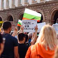 Protestors outside a government building holding signs and flags in Sofia, Bulgaria 