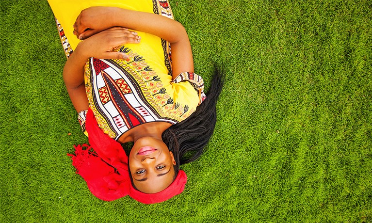 A woman laying on the grass smilling up to the camera