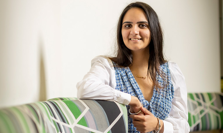 Rhemat sitting on a sofa smiling at the camera