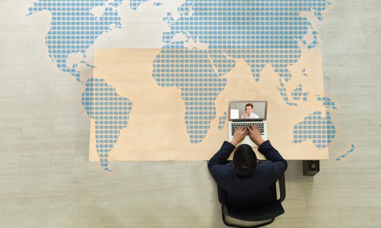 Top down view of man working at desk on laptop.