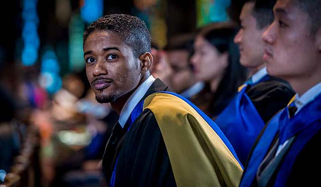 Graduate at graduation ceremony in robe looking at camera