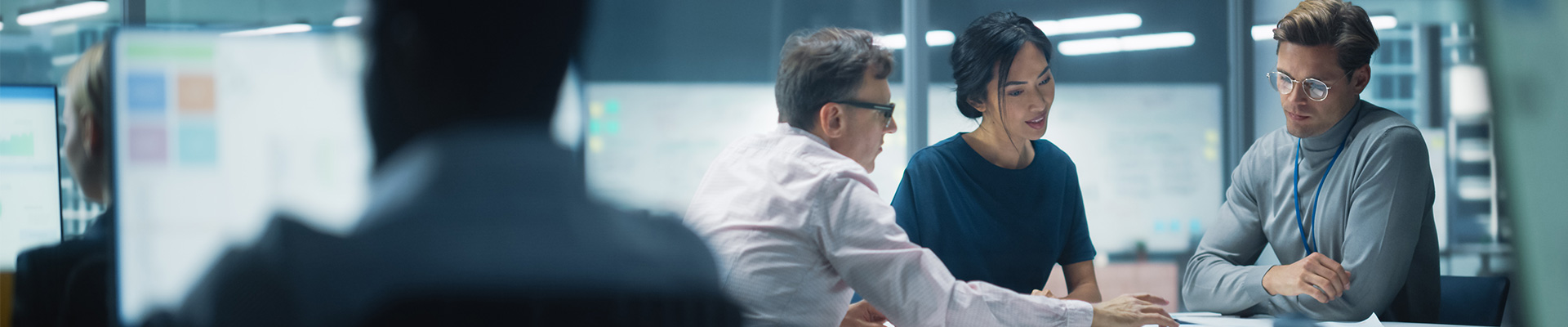 A diverse team of managers working and having a discussion around a table in a modern office.