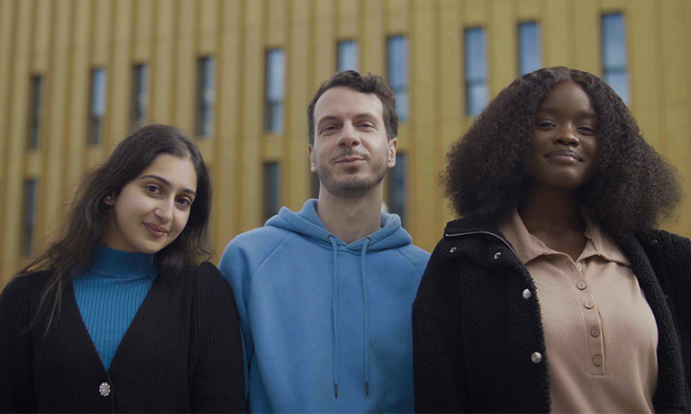 Three students stood together in front ov a Coventry University campus building.