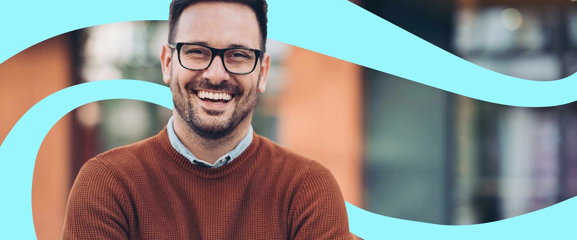 Smiling male wearing glasses with folded arms looking forward. There is graphic blue turquoise swirls in the background