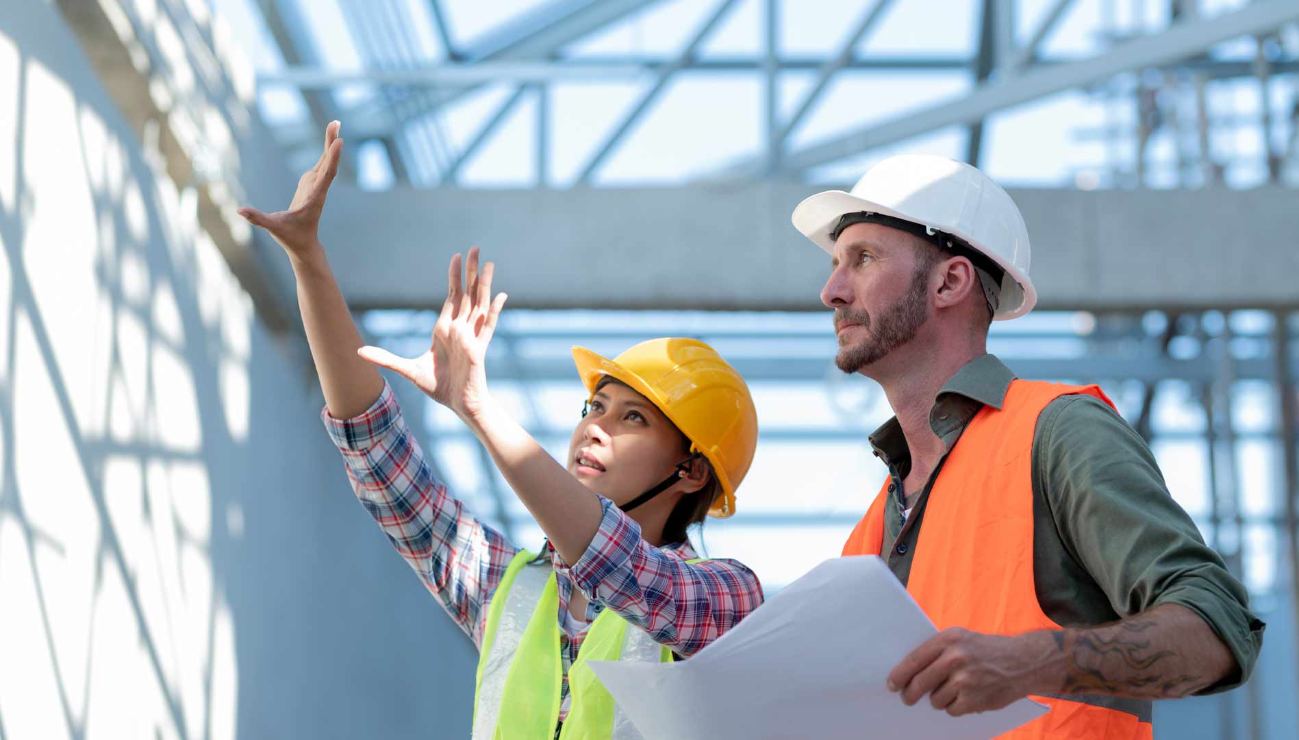 Male and female wearing hard hats pointing at scaffolding