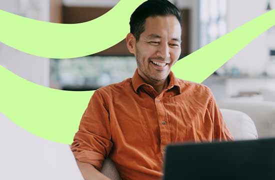 Smiling older asian man looking at a laptop with a green swirl in the background