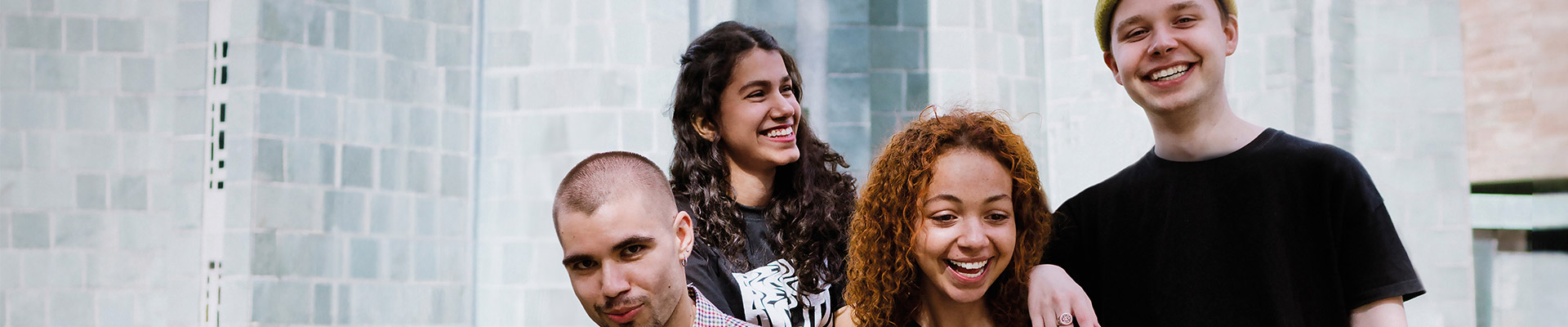 A group of four students smiling outside on campus.