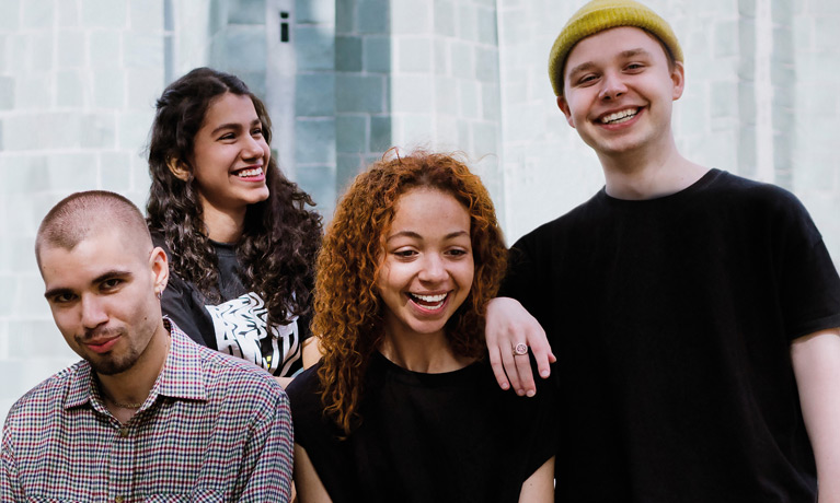 4 students smiling and laughing outside 