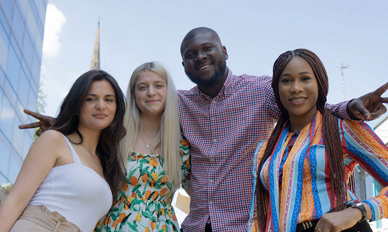 3 female students and 1 male student with their arms around them smiling looking at the camera