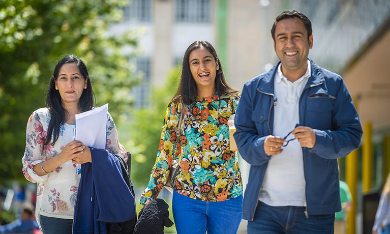 Female student walking with her parents in the campus 