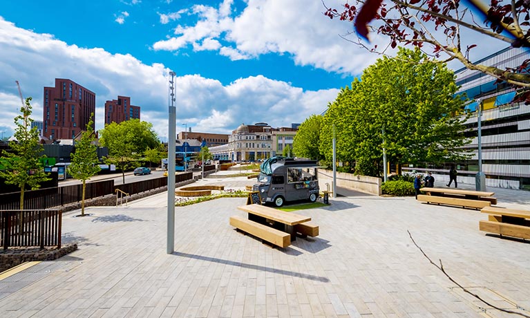 A blue sky over a large open air garden seating area on the Coventry campus.