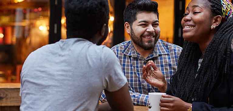 3 students sitting in the outside area of the bar socialising