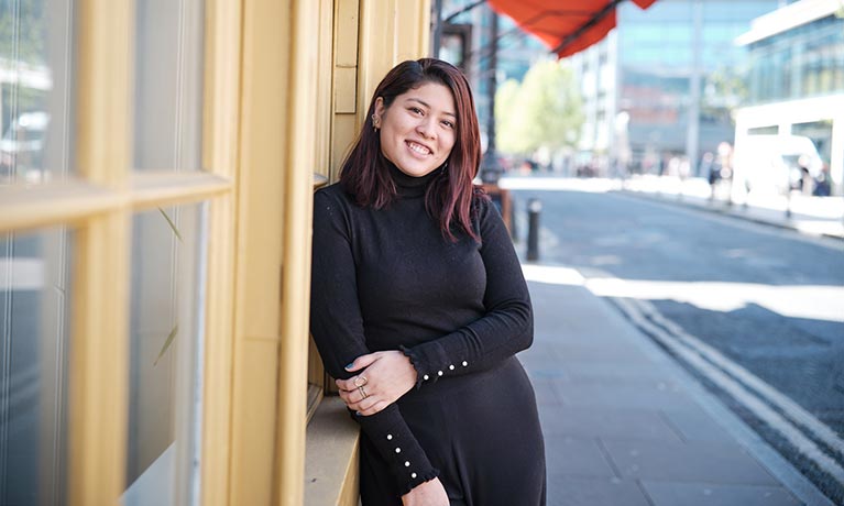 student leaning against a shop front on a street in London