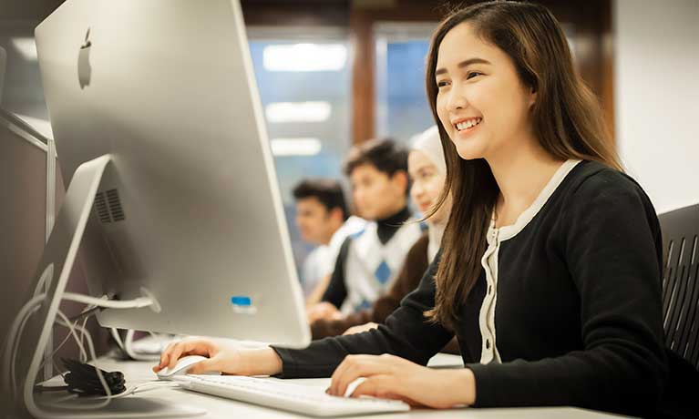 A Coventry University London student working on their laptop in a study areandon