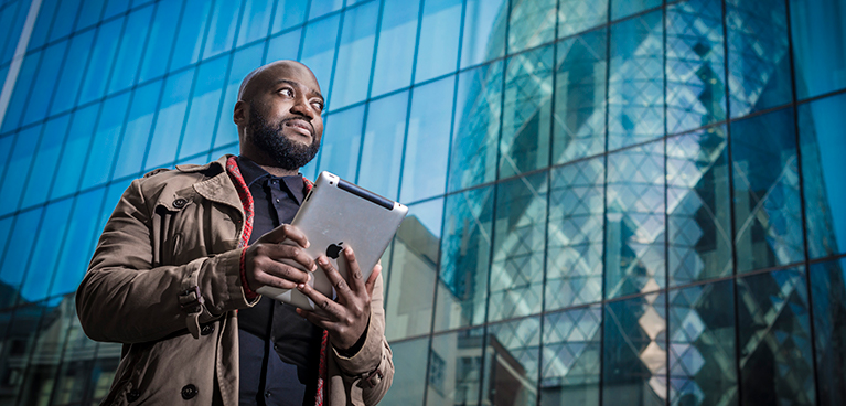 Man holding an ipad infront of a glass building