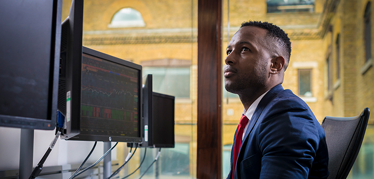 Professional male in a shirt tie looking at multiple screens 