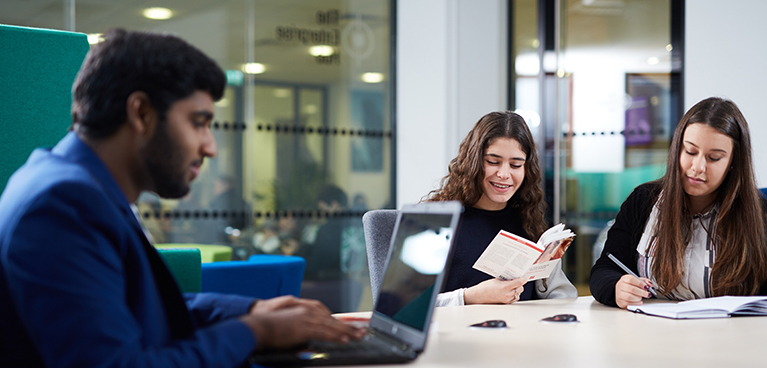 students working at a table in a study room