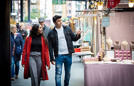 Couple walking on London streets, through a market.