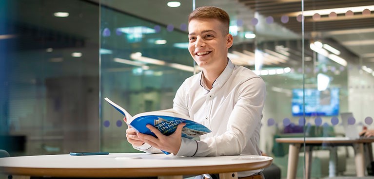 man sitting at a desk holding a book 