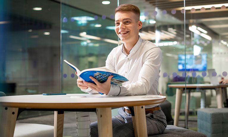 A student in an open study area with a textbook