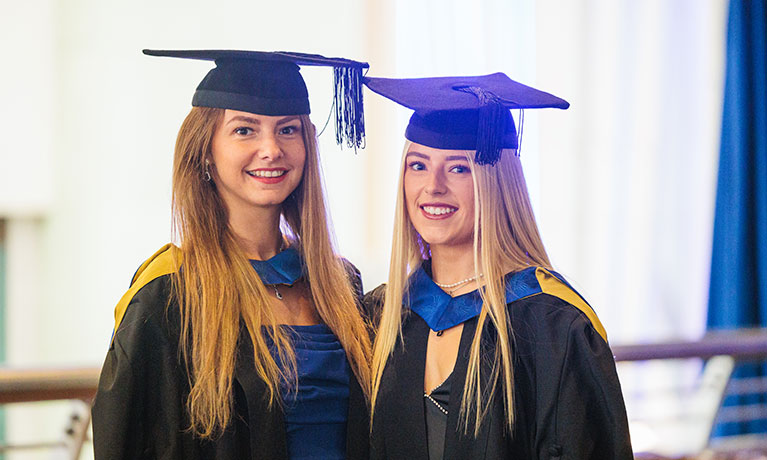 Two smiling new graduates, Taame is on the left