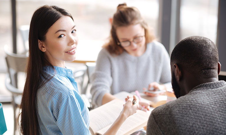 group sitting at a table as a  women smiles for a photo.