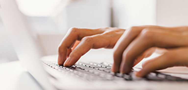 close up of fingers typing on a laptop