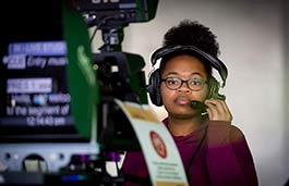 Female student in a TV studio working a camera. 