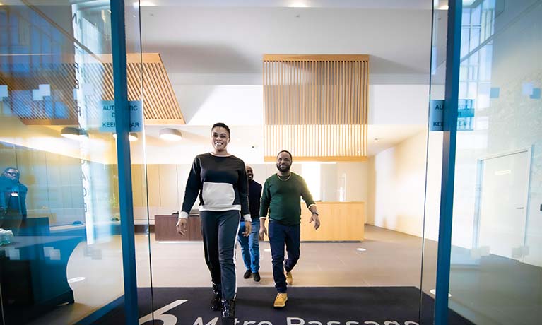 Three students walking out of the Greenwich building