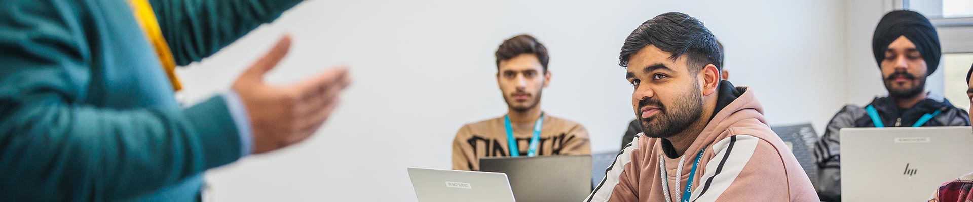 Group of students sat in a classroom with a lecturer stood at the front