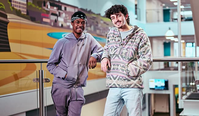 Two students leaning against a balcony talking