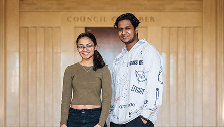 Two students stood together smiling