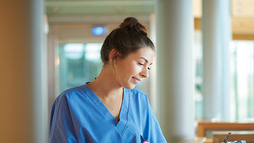 Young female nurse looking after her patients white wearing a light blue top