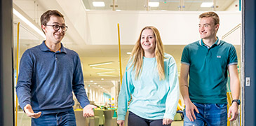 Three students talking whilst walking out of reception in CU Scarborough 