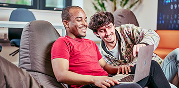 Two male students sat on bean bags looking at a laptop