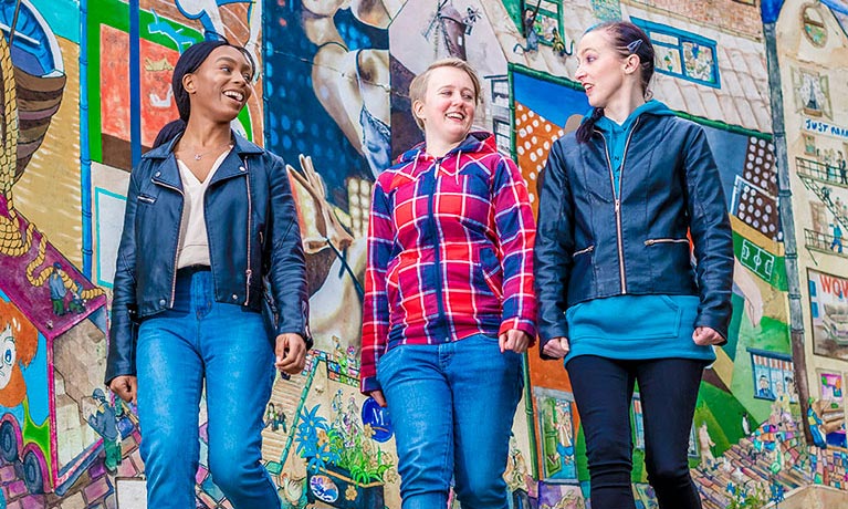 Students walking together infront of a colorful wall