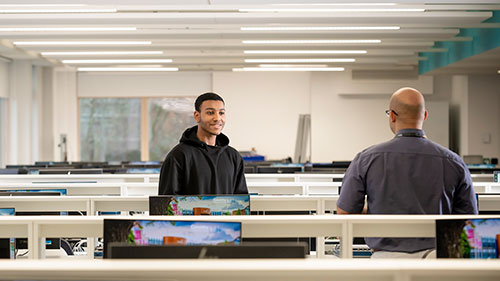 Cloud Computing student talking with tutor in a computer room