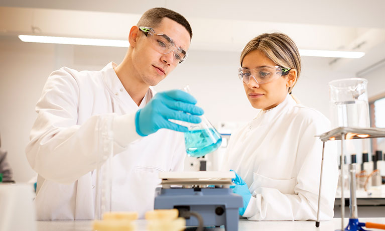 Two students in lab coats working in a laboratory