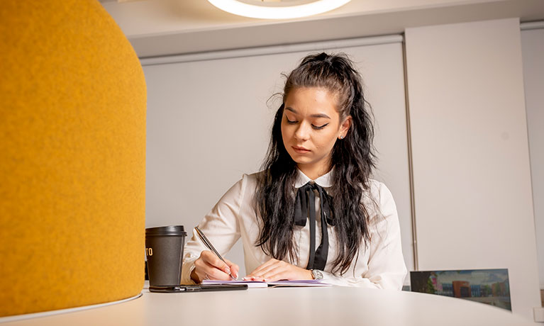 Female student sat at a desk taking notes