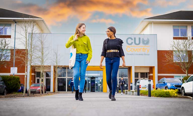 Two students talking whilst walking away from the CU Coventry campus