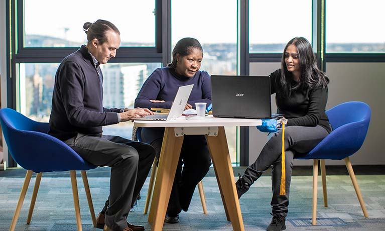 Three students sat at a table working