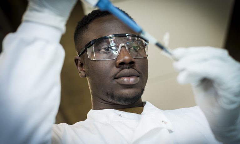 Black student filling a syringe in a laboratory 