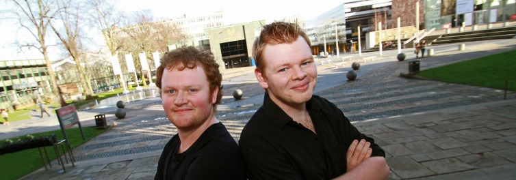 Two muscians Jon and Seb back to back smiling outside Coventry University campus