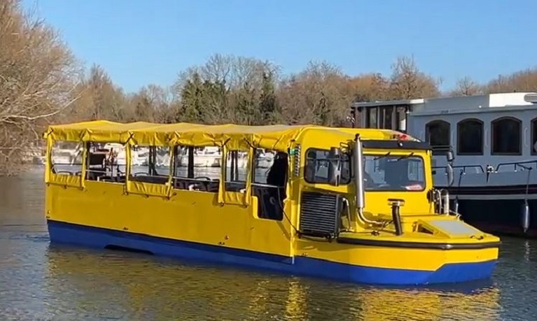 A yellow amphibious bus travelling along a river
