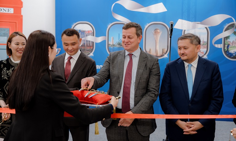 Richard Wells picks up a pair of gold-handled scissors ready to cut the ribbon at opening of Coventry University Kazakhstan while stood next to other dignitaries