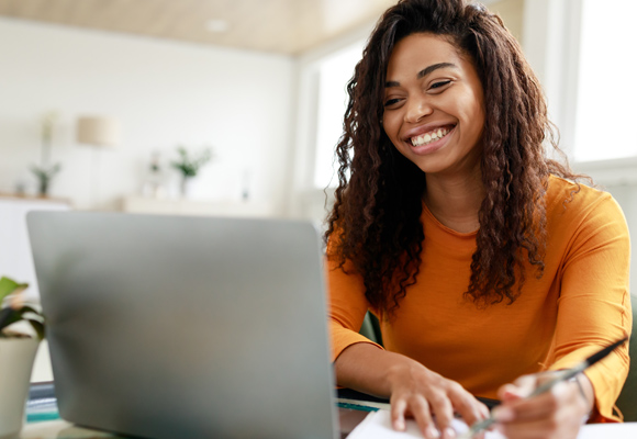 A student smiling while using their laptop. 