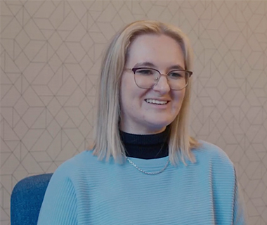 Headshot of Lucy Roberts in a blue sweater smiling at the the camera.