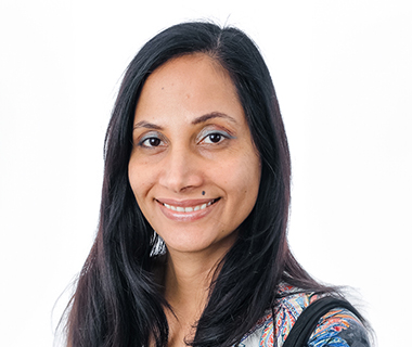 Portrait headshot of Mandeep Chahal smiling at the camera against a white background.