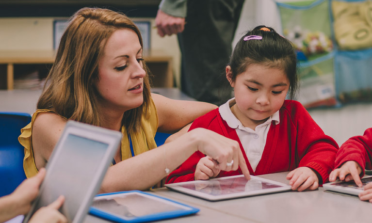 teacher helping young student in a classroom